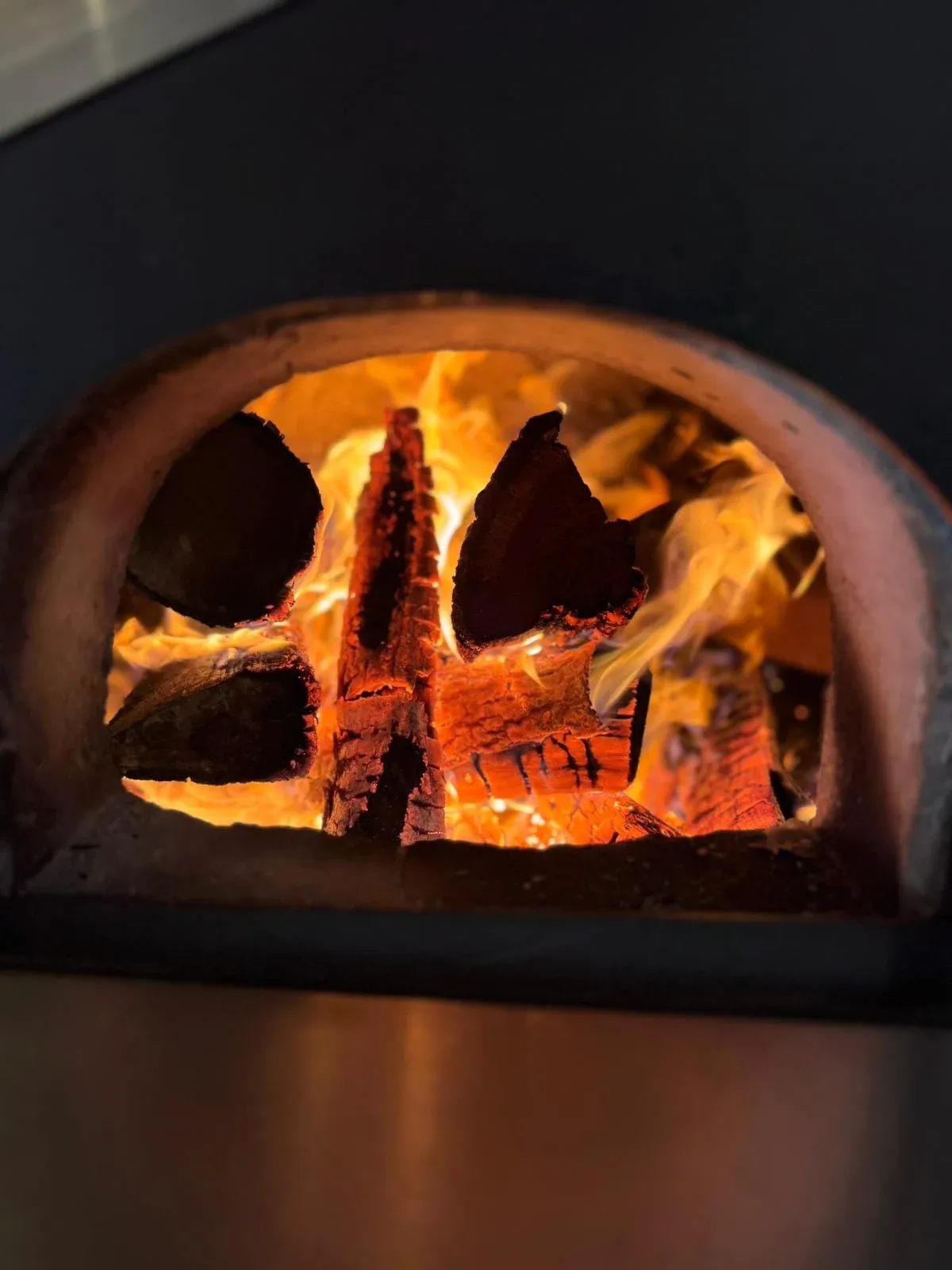Flammes et feu de bois dans le four à pizza traditionnel de la pizzeria Chez Matteo au Porge.